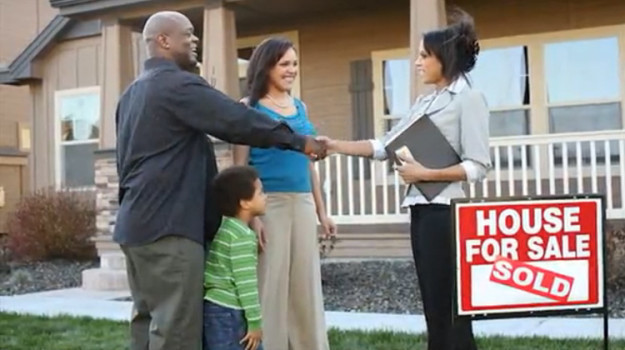 Photo of family shaking hands with Realtor in front of sold home